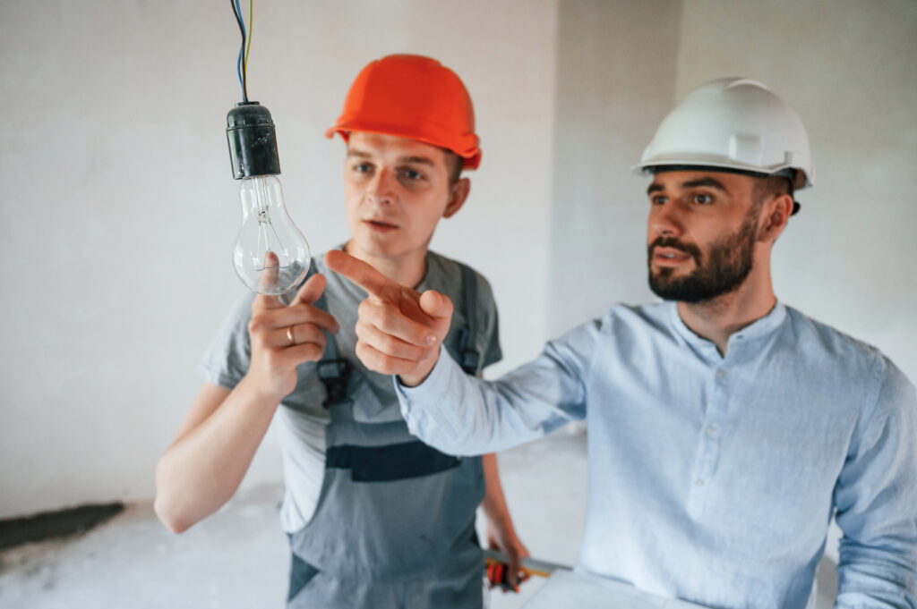 Working with light bulb. Two men is making repairs in the apartment together.