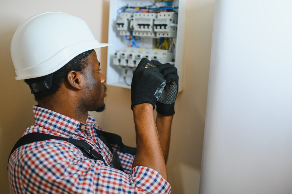 African american electrician Repairing electricity switchboard.