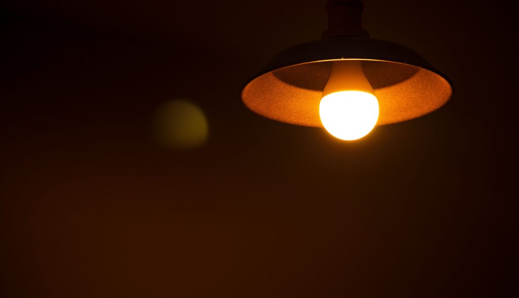 A closeup of a vintage light bulb illuminating a dark room