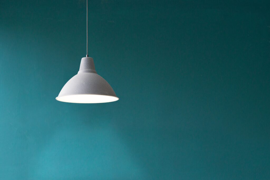 A pedant white lamp hung in front of a blue wall