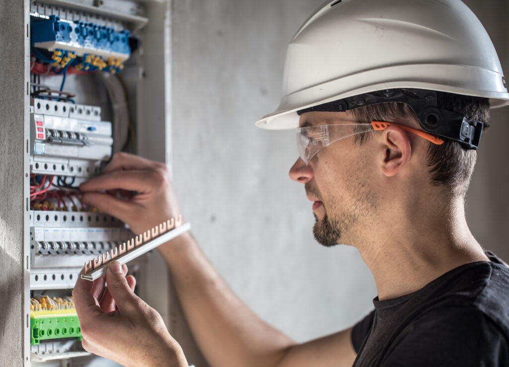 Man, an electrical technician working in a switchboard with fuses. Installation and connection of electrical equipment.