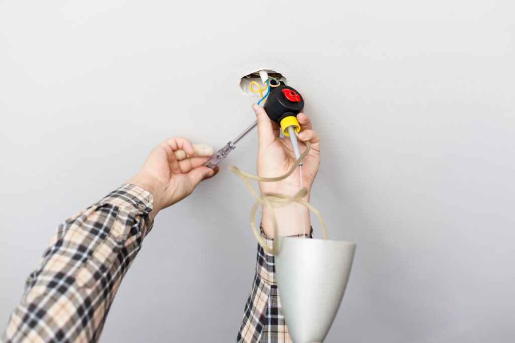 man repairing defected ceiling lamp at home