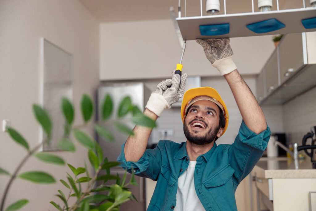 Electrician worker is installing electric lamps light in kitchen. Construction decoration concept